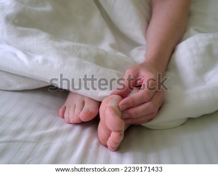 female legs on a white bed. The problem with women's feet. Hallus valgus, closeup