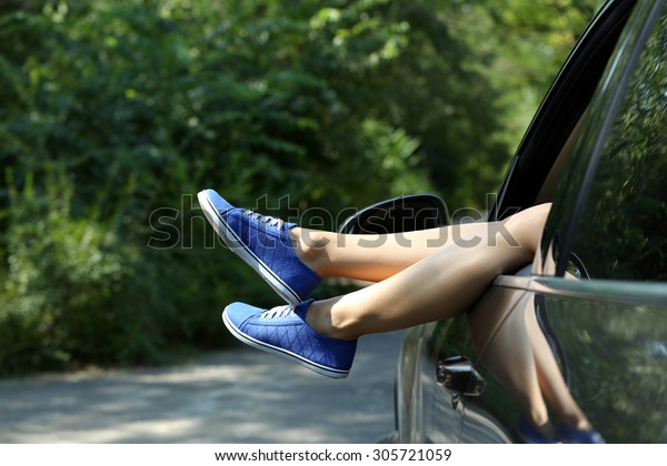 Female legs out
car window on nature
background