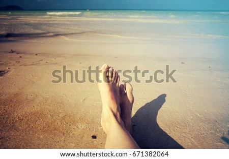 Female legs over tropical beach background 