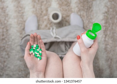 Female Legs, Pills On The Hand, Open White Container Of Medicine, Close Up, Sitting On Toilet, Top View