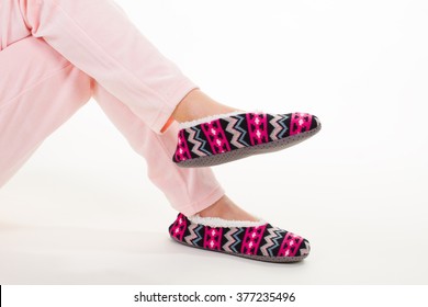 Female Legs In Pink Pajama Pants And Bright Slippers On A White Background.