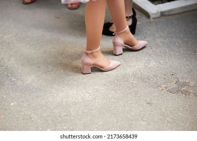 Female Legs In Pink Summer Open Shoes On The Pavement, Close-up Of The Legs. Selective Focus