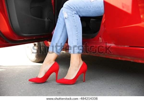 Female legs in red\
shoes from opened car\
door