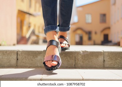 Female legs in sandals descending the stairs in the city