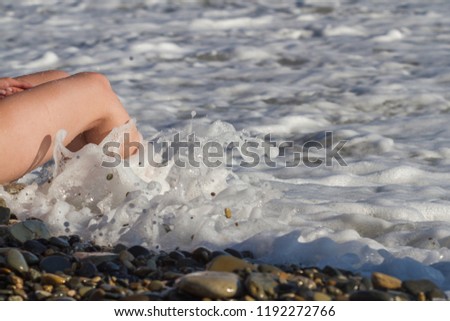 Female legs in the sea wave