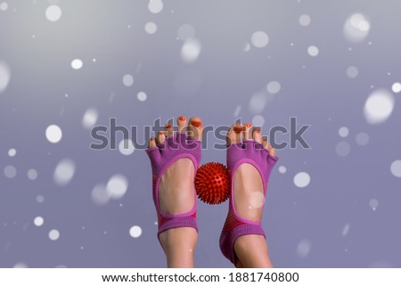 Female legs with small ball for trigger zones over winter background with snowflakes