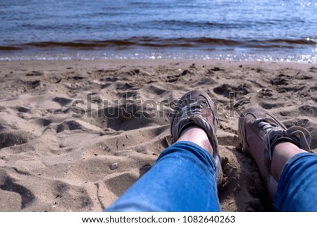 Female legs in sneakers on a sand. Relax on the beach.