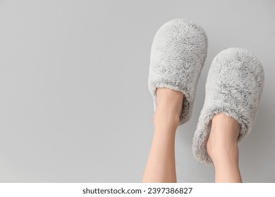 Patas femeninas con zapatillas suaves sobre fondo gris