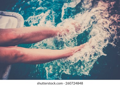 Female legs splashing sea water from a sailing yacht. Filtered shot