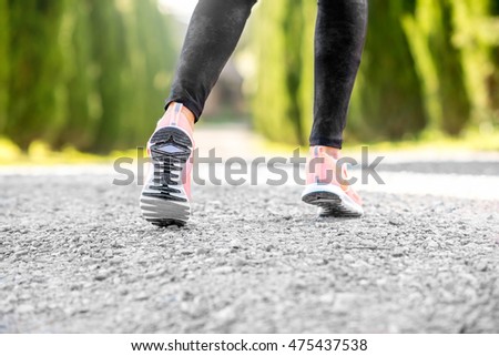 Female legs in sport sneakers in start position on the gravel road