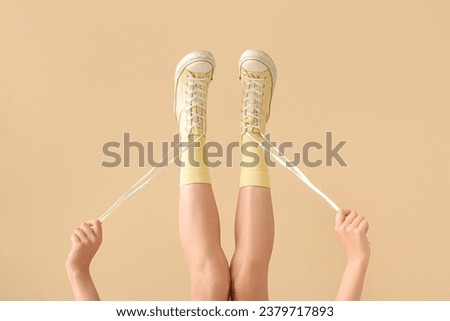 Female legs in stylish gumshoes against color background