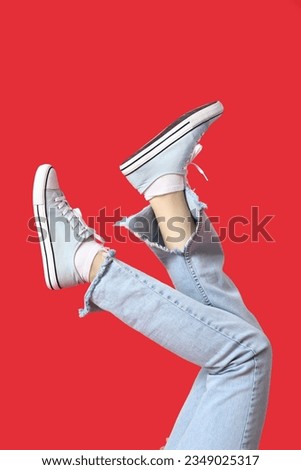 Female legs in stylish gumshoes on red background, closeup
