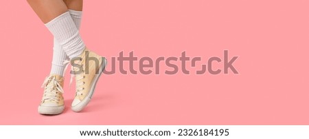 Female legs in stylish gumshoes and white socks on pink background with space for text