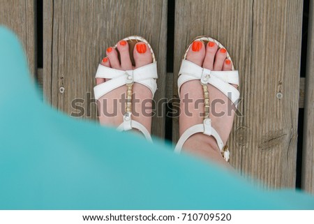 
female legs in summer sandals on a wooden background