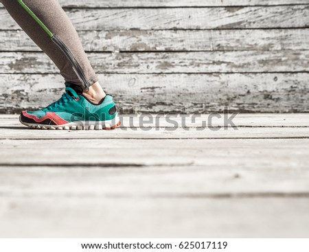 female legs in tights and sports shoes on wooden background ,concept sports