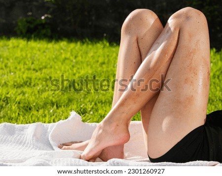 Female legs with trace of cheap fake sun tan. The model is on a sun lounger on a grass in a backyard or park. Using poor quality body care product concept.