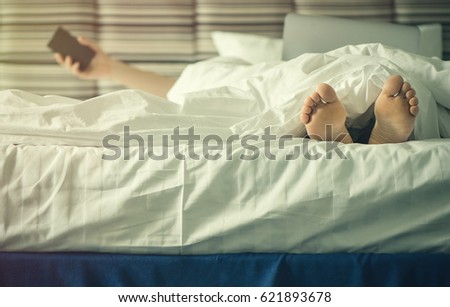Female legs under blanket at sunset. Female with laptop in the blur