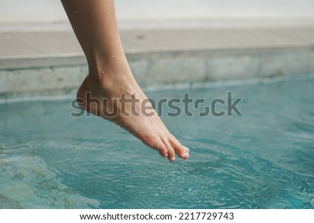a female legs in the water pool on the edge of a pool