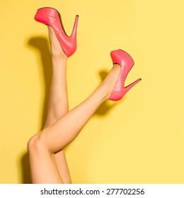 Female Legs Wearing Summer High Heels Over Yellow Background