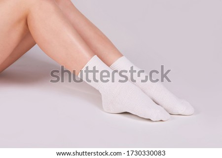 Female legs in white cotton socks on white background. Ladies wearing sports socks
