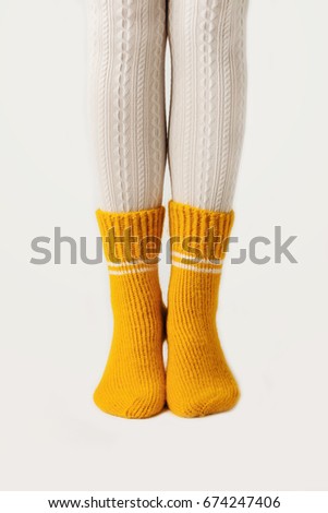 Female legs in white stockings and yellow knitted socks.