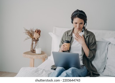 Female Life Coach, Teacher Freelancer Wearing Wireless Headset, Teaching Online, Conducts Consultation, Remote Webinar By Video Call On Laptop Computer, Sitting In Bedroom At Home.