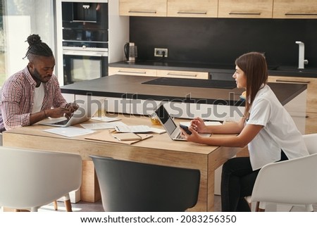 Female looking at serious guy typing on his laptop