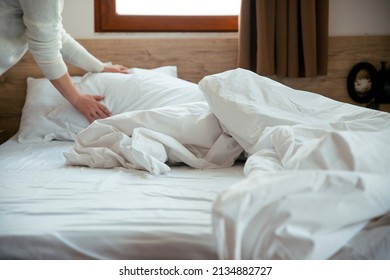 Female Makes The Bed In The Bedroom. Maid Cleaning Messy Hotel Bed Cushion And Duvet, Changing Bed Sheets With Clean Selective Focus. Copy Space