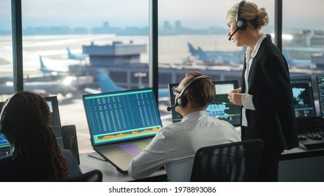 Female and Male Air Traffic Controllers with Headsets Talk in Airport Tower. Office Room is Full of Desktop Computer Displays with Navigation Screens, Airplane Flight Radar Data for the Team. - Shutterstock ID 1978893086