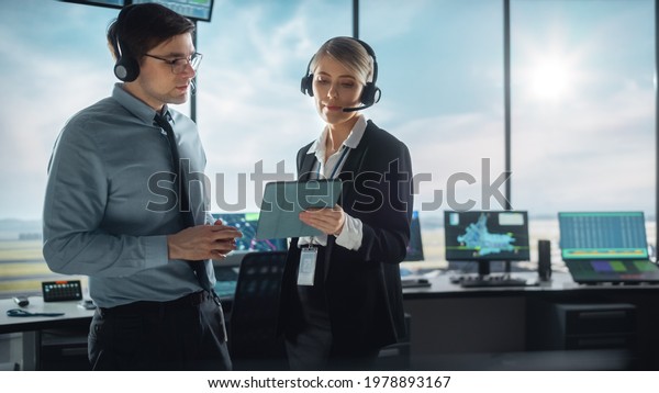 Female and Male Air Traffic Controllers with\
Headsets Talk in Airport Tower. Office Room is Full of Desktop\
Computer Displays with Navigation Screens, Airplane Departure and\
Arrival Data for the\
Team.