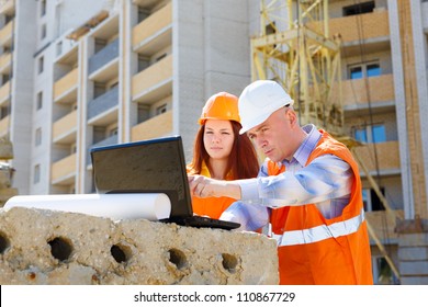 Female And Male Construction Workers Looking At Laptop