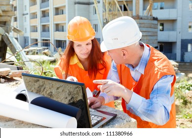 Female And Male Construction Workers Looking At Laptop