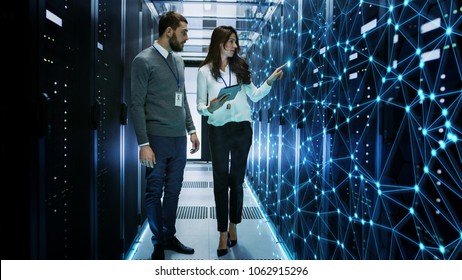 Female and Male IT Engineers Discussing Technical Details in a Working Data Center/ Server Room with Internet Connection Visualisation. - Powered by Shutterstock