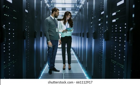 Female and Male IT Engineers Discussing Technical Details in a Working Data Center/ Server Room.
