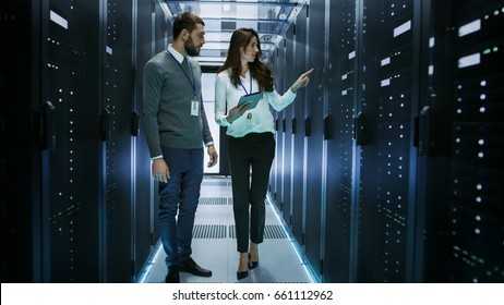 Female and Male IT Engineers Discussing Technical Details in a Working Data Center/ Server Room. - Powered by Shutterstock