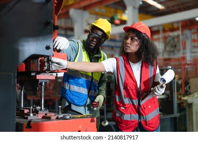 Female and Male engineers in safety vest checking and repairing machine at factory.Preventive Maintenance concept