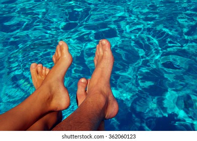 Female and male feet against blue water of the pool. Feet in the pool. Rest near the pool