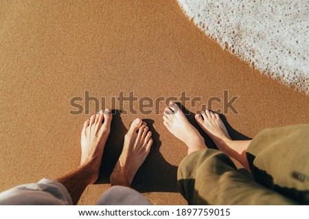 Female and male feet on the sandy beach. Sea rest