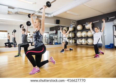 Female And Male Friends Lifting Barbells In Gym
