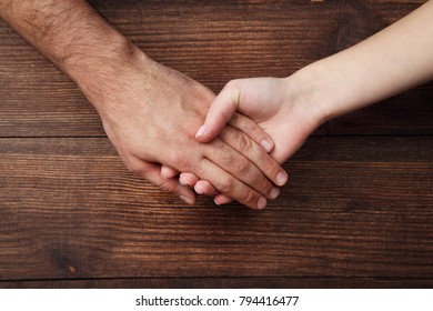 Female and male hand holding each other on brown background