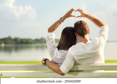 Female And Male Hands Making Up Heart Shape Over Blue Sky 