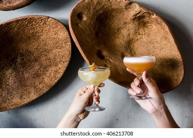 Female And Male Holding Citrus Alcoholic Cocktails Yellow And Orange (pisco Sour) 