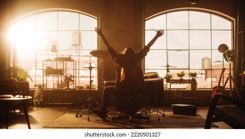 Female Or Male With Long Hair Sitting With Their Back To Camera, Playing Drums During A Band Rehearsal In A Loft Studio. Heavy Metal Drummer Practising A Drum Solo Alone At Home.