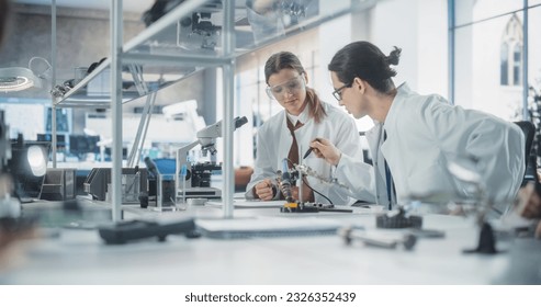 Female and Male Students in Safety Goggles and White Coats Working Together in Science Class, Collaborating on a College Project. Scholars Talking, Study and Prepare for Computer Engineering Exams