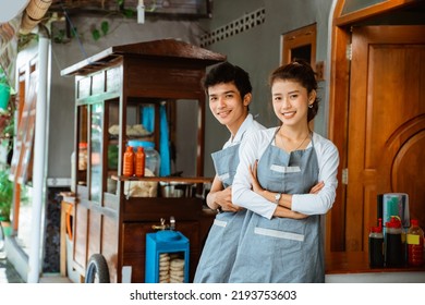 female and male traders smiling with arms crossed at a chicken noodle cart stall