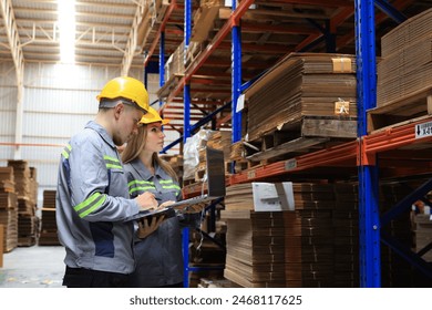 Female and male workers use laptop  working in paper warehouse, International car part, import export and logistic business concept. Logistics, transportation, distribution, industry factory concept. - Powered by Shutterstock