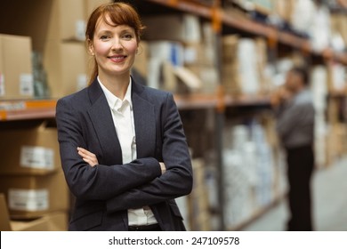 Female manager with arms crossed in a large warehouse - Powered by Shutterstock