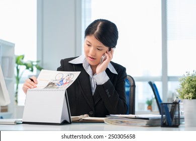 Female Manager Looking At The Calendar While Talking On The Phone