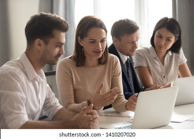 Female manager mentor teach help male intern trainee new employee explain online strategy on laptop at group meeting, focused business woman talk to colleague client work together cooperate in office