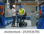 Female manager training a new employee with a disability for a job, explaining work on machines. Industry, inclusion and workplace concept.